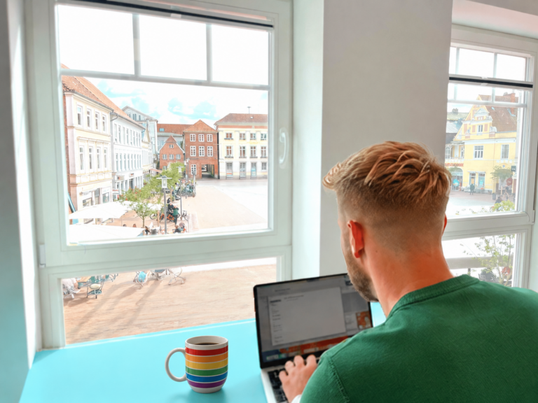 Person arbeitet am Laptop bei coworking.eutin, einem sicheren Ort zum Arbeiten mitten in Eutin, mit Blick auf den Marktplatz